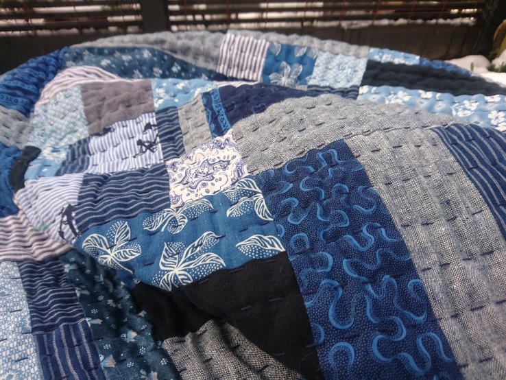 a close up photo of a blue rail fence quilt, handquilted with a long running stitch with sashiko thread
